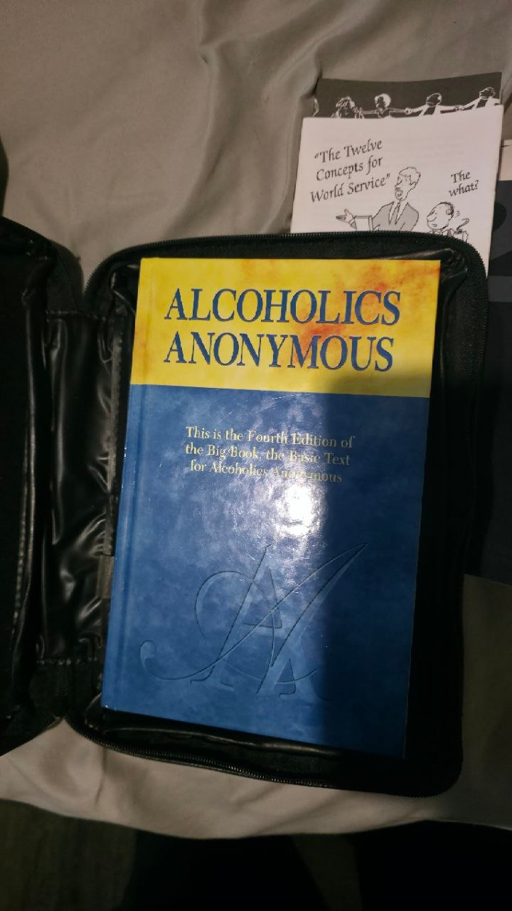 A near-pristine 4th Edition Big Book, yellow and blue jacket, lying inside its opened black case.