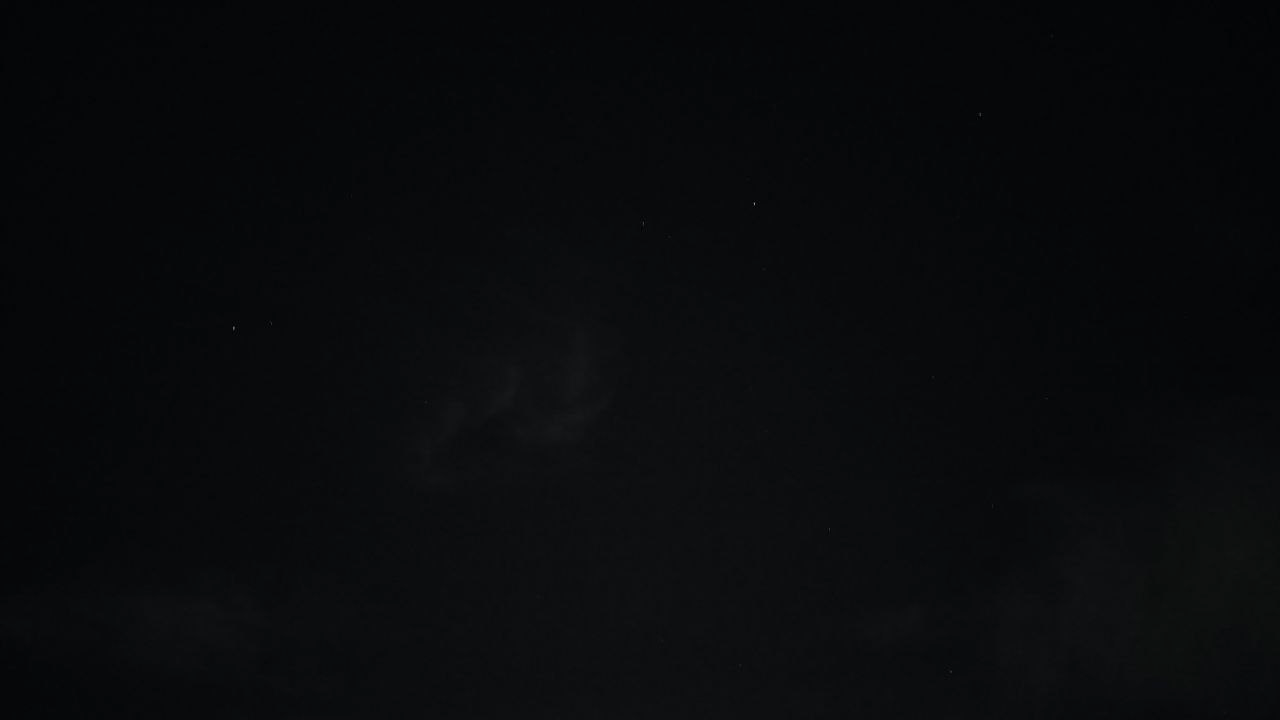 A nearly black night sky with thin grey cloud wisps and a handful of faint stars.