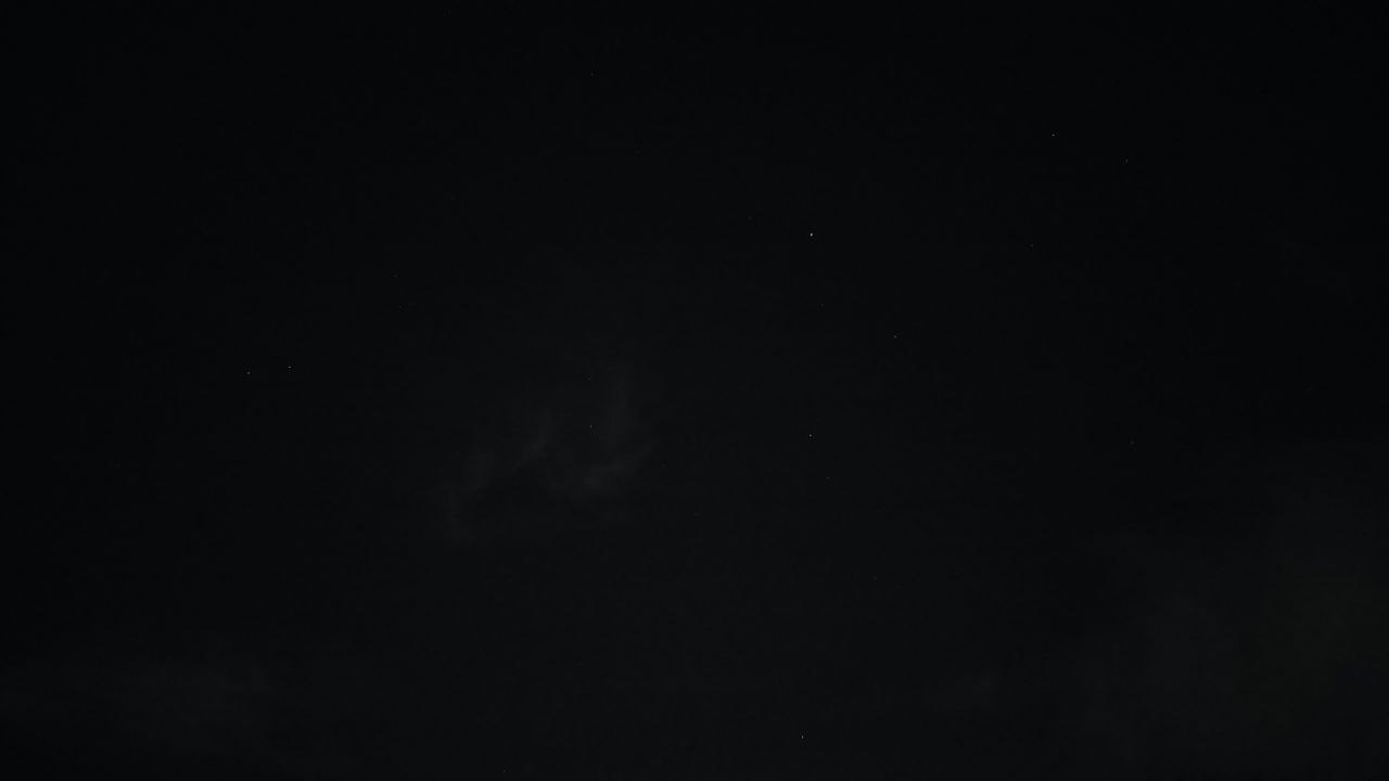 Another nearly black frame: faint cloud, five or six dim pinpricks of starlight.